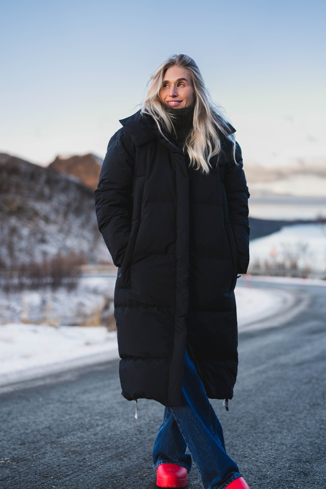 Kvinne i lang sort dunkåpe fra Blæst på en vintervei